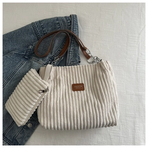 Detail of off-white corduroy tote bag set with chain strap and leather patch logo