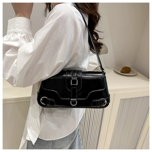 Détail du sac d'épaule en similicuir noir brillant avec boucle argentée et bandoulière