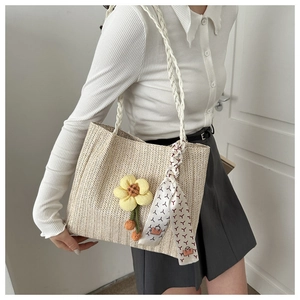 Détail du sac cabas en paille tissé avec breloque fleur et foulard en soie imprimé