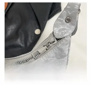 Close-up of metallic silver bow shoulder bag featuring a smooth metal zipper detail