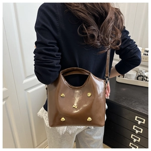 Brown leather tote bag with gold animal studs shown on a model for scale and style