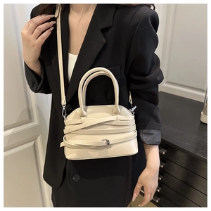 Detail of cream crossbody bag with distinctive criss-cross strap and silver buckle accent