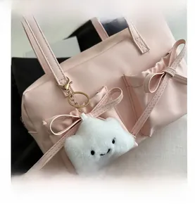 Détail du sac à bandoulière en cuir rose avec nœud latéral et charm nuage en peluche