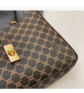 Dettaglio borsa a tracolla marrone vintage con chiusura in metallo dorato e stampa monogram