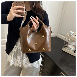 Detail of dark brown leather tote with golden paw and bone shaped metal hardware