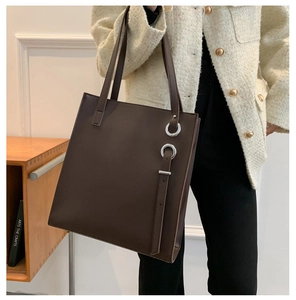 Detail of dark brown leather tote bag with silver metal ring and side strap decoration