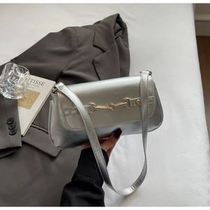 Detailed view of silver metallic shoulder bag with crinkled texture and gold horsebit buckle