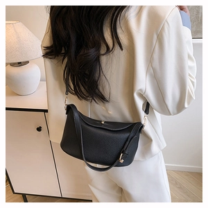 Classic black litchi texture pillow bag shown on white suit model in a modern scene
