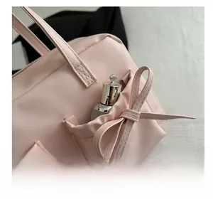 Détail d'un sac à main rose montrant une poche latérale avec nœud décoratif et coutures