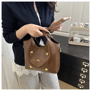 Detail of brown patent leather bag featuring golden puppy and bone-shaped hardware charms
