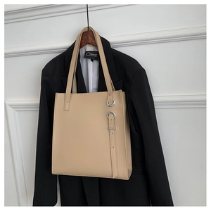 Detail of beige faux leather tote bag with vertical buckle strap and long shoulder strap