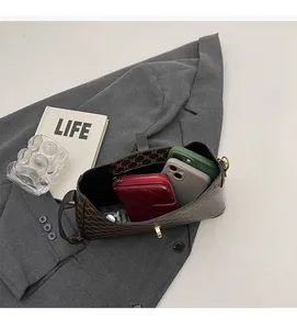 Interno spazioso di una borsa sottobraccio marrone con monogramma contenente portafoglio e telefoni