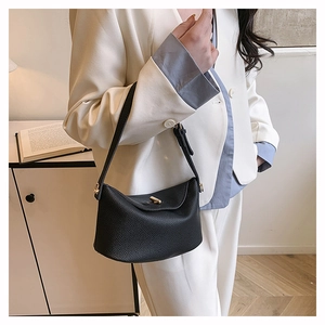 Close-up of black litchi leather handbag with gold metal twist lock and dual handles