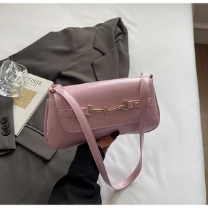 Pink retro shoulder bag with gold horsebit hardware shown on a grey blazer and white bedding