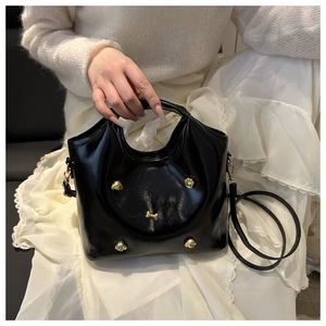 Detail of black glossy handbag with golden dog-shaped buckle and leather strap