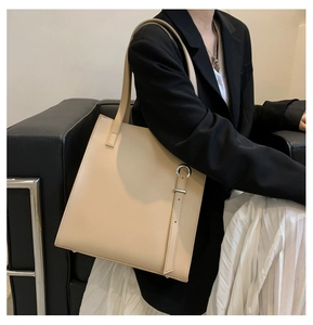 Detail of a beige PU leather tote bag featuring a silver metal ring and decorative strap