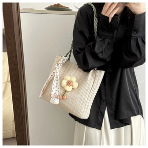 Détail de texture du sac seau tissé beige avec breloque fleur et poignée foulard élégante
