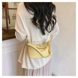 Pale yellow leather crossbody bucket bag worn by model showing size and styling
