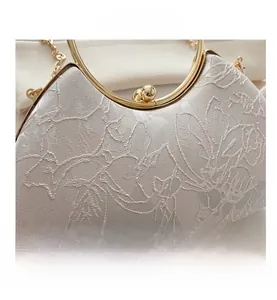 Detail of evening clutch bag with cream lace embroidery and gold ring handle