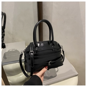 Close-up of black patent shell bag with multi-strap buckle details and silver hardware