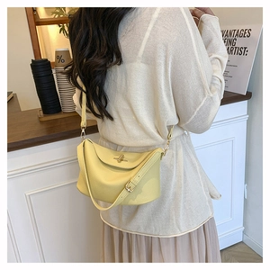 Macro detail of light yellow litchi grain leather bag with vintage metal clasp closure