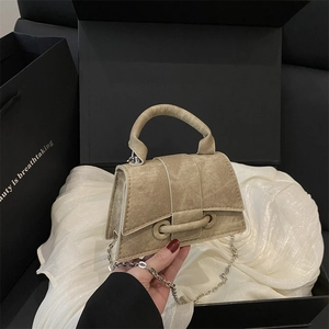 Elegant beige canvas hourglass handbag with silver chain strap on silk background