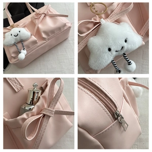 Detail view of pink bow shoulder bag with plush cloud charm and zipper storage