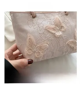 Dettaglio del ricamo a farfalla 3D e della trama in pizzo sulla borsa rosa elegante
