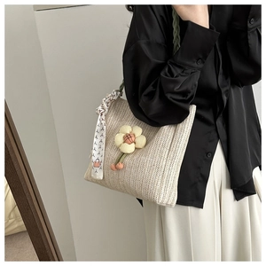 Détail du sac cabas en paille tissée avec breloque fleur 3D et foulard en soie