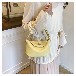 Detailed view of yellow lychee leather handbag with elegant metal lock and shoulder strap