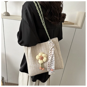 Détail du sac seau en paille tressée avec breloque tournesol et foulard en soie décoratif