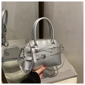 Detail of silver metallic handbag featuring decorative straps and metal buckles design