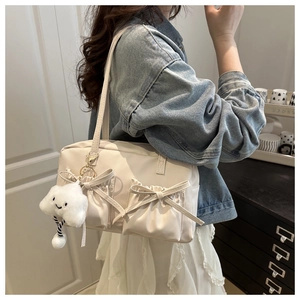 Detail of cream shoulder bag featuring drawstring bow pockets and cloud charm accessory