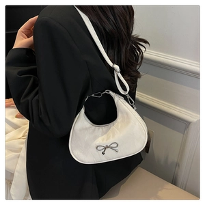 Detail of white crescent bag with silver bow ornament on textured faux leather