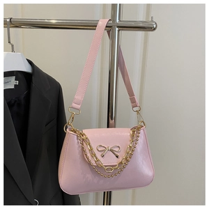 Pink patent leather underarm bag with golden bow hardware and decorative chains