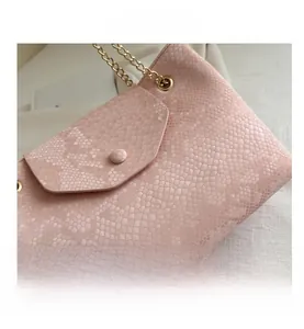 Gros plan du sac en cuir rose à texture serpent avec détails de chaîne dorée