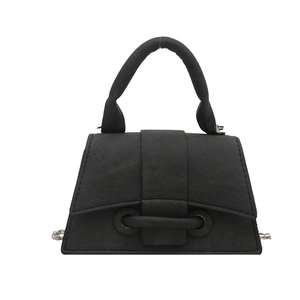 Minimalist black trapezoid handbag with textured fabric and unique buckle detail