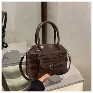 Detail of dark brown patent leather handbag featuring silver metal buckles and straps