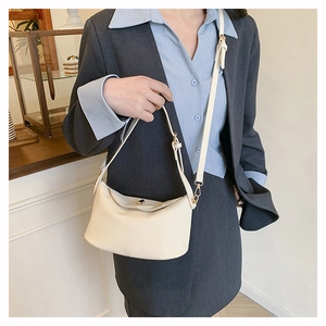 Close-up of off-white lychee grain leather handbag with golden metal twist lock detail