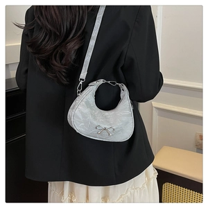 Detailed view of silver metallic crescent bag featuring bow buckle and smooth texture