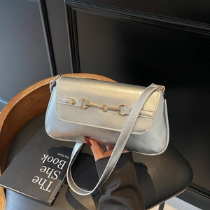 Retro silver leather baguette shoulder bag with gold horsebit buckle on black background