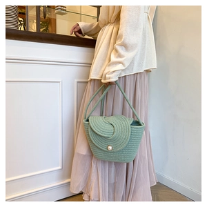 Detailed close-up of woven shoulder bag with unique spiral texture and pearl closure