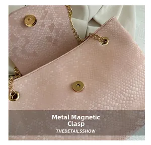 Detail of pink faux snakeskin leather bag with gold magnetic buckle and metal chain strap