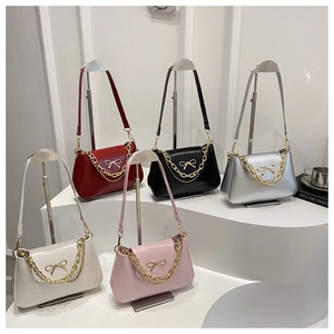 Detail of minimalist leather shoulder bags in five colors with gold bow and chain accents