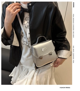 Dettaglio borsa a tracolla argento con fibbie in metallo su outfit in pelle nera stile