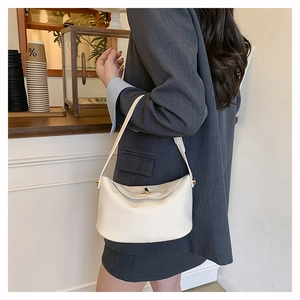 Detail of a creamy white lychee grain leather bag with a golden rotating metal lock