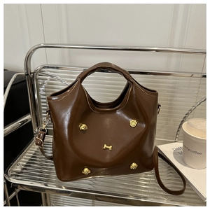 Detailed close-up of dark brown glossy bag featuring golden puppy-themed metal studs
