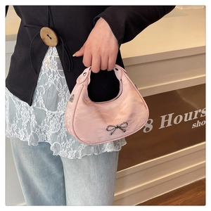 Detailed shot of pink crescent bag with pleated silk texture and silver bow detail