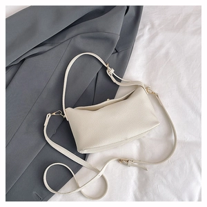 Detail of lychee pattern leather handbag with adjustable gold buckles and beige texture