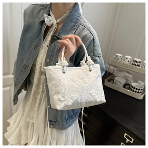 Detail of white lace handbag featuring 3D butterfly embroidery and silver metal rings